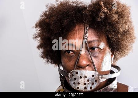 Face portrait of black woman with iron mask of slavery covering her mouth. Studio reproduction. Stock Photo