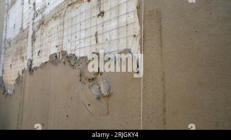 Repair of the outer wall of the building with the use of putty. Close-up of manual workers plastering cement on a wall structure. Washing putty with a Stock Photo