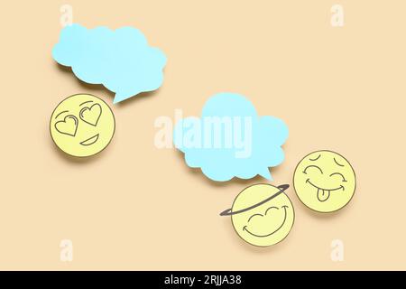 Paper faces with blank speech bubbles on beige background Stock Photo