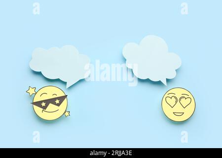 Paper faces with blank speech bubbles on blue background Stock Photo