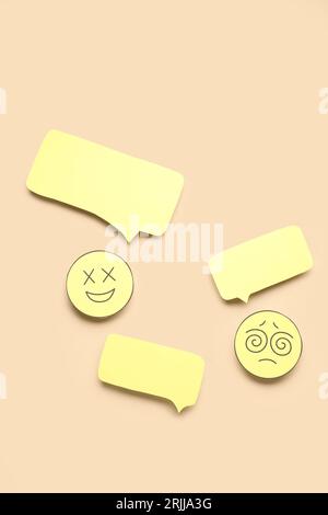 Paper faces with blank speech bubbles on beige background Stock Photo
