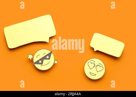 Paper faces with blank speech bubbles on orange background Stock Photo