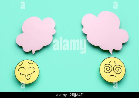 Paper faces with blank speech bubbles on turquoise background Stock Photo