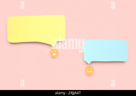 Paper faces with blank speech bubbles on pink background Stock Photo