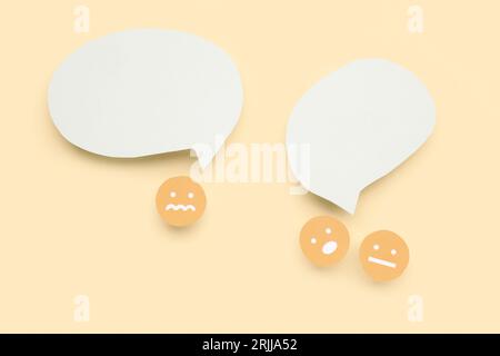 Paper faces with blank speech bubbles on yellow background Stock Photo