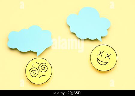Paper faces with blank speech bubbles on yellow background Stock Photo
