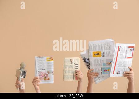 Female hands with different newspapers and microphone on color background Stock Photo