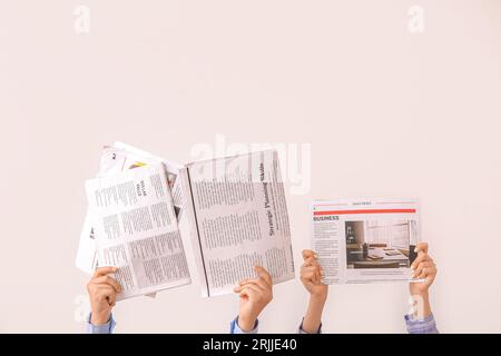 Female hands with different newspapers on light background Stock Photo