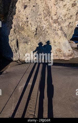 Shadows cast by setting sun on pair of hikers at Point of Arches, Olympic National Park, Washington State, USA Stock Photo