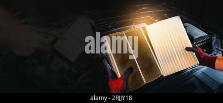 Auto mechanic compares a clean new air filter to an old, auto mechanic changing car air filter, panoramic banner with copy space for text, car mainten Stock Photo