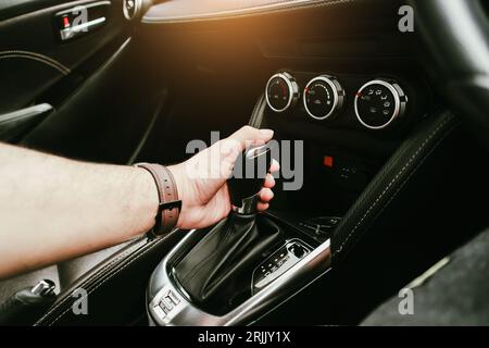 Driver hand holding gear lever of automatic transmission and hand moves the gear lever in the car, The driver shifts into gear to drive and travel, Au Stock Photo