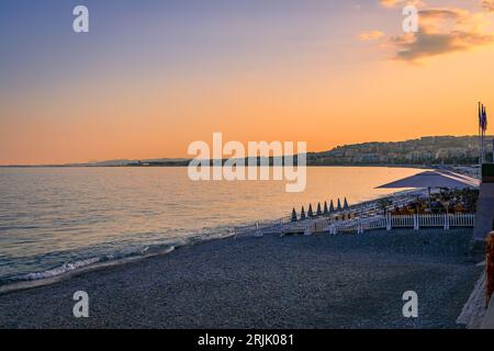 Sunset at an empty beach by the famous Promenade des Anglais with the Mediterranean Sea and a beachfront restaurant in the background in Nice, France Stock Photo