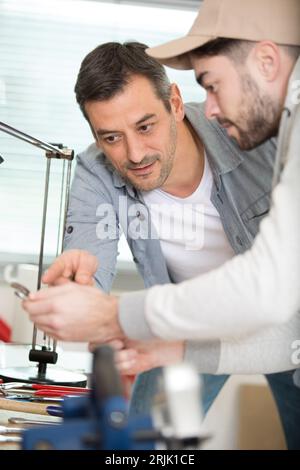 two men working as craftsmen together in carpenters shop Stock Photo