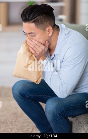 stressed asian man breathing with paper bag Stock Photo
