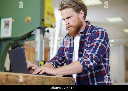 woodworker using laptop in his workshop Stock Photo