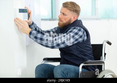 disabled electrician installing alarm system Stock Photo