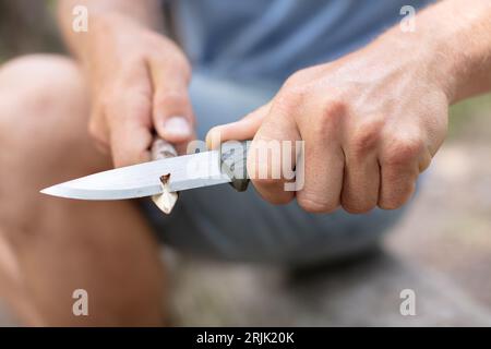 young man with a knife cut a wooden stick Stock Photo