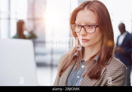 businesswoman or female executive manager in formal suit and eyeglasses, holding laptop and using laptop computer. Stock Photo