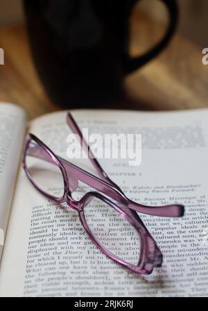 Eyeglasses, Book and Coffee. Directly above shot of Book, eyeglasses and with a cup of coffee on a wooden table. Stock Photo