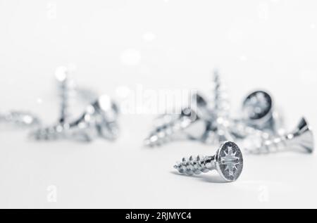 Screws, self-tapping screws are randomly scattered on the table. A bunch of galvanized screws. Stock Photo