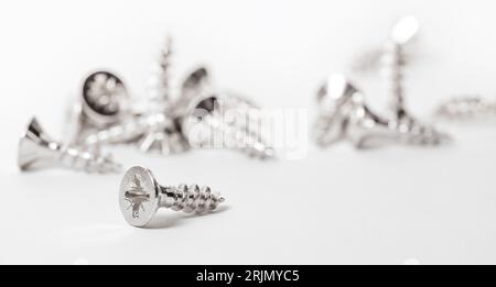 Metal screws scattered, industrial background. Steel screws, metal screw, iron screw, screws as a background, wood screw. Stock Photo