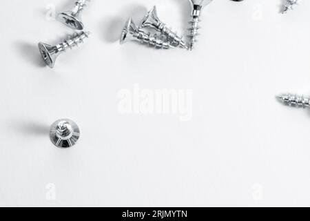 Pile of screws lie on a white surface. Stock Photo