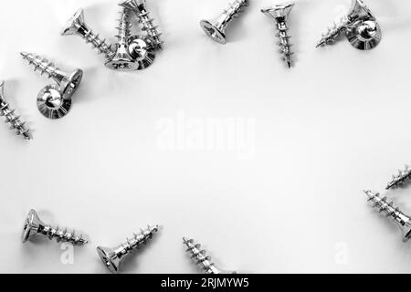 Pile chrome screws on scratched metal background. Stock Photo