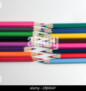 Collection crayons colored pencils loosely arranged on drawing paper. Stock Photo