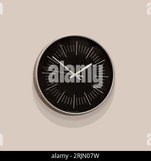 Abstract black wall clock on a beige wall with soft shadows. Stock Photo