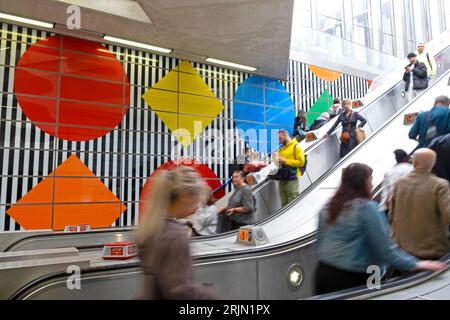 People travellers on the Elizabeth Line underground tube escalator with colourful wall designs at Tottenham Court Road Station London UK  KATHY DEWITT Stock Photo