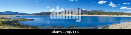 A panoramic view of a lake in a secluded area of the mountains, surrounded by lush green vegetation Stock Photo