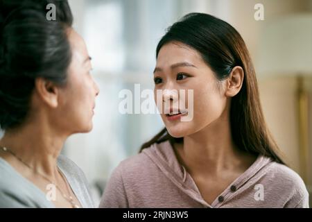 young asian adult daughter consoling senior mother living with mental illness Stock Photo