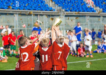 School Kids in Sports Team Winning Championship. Happy Children Holding and Rising Up Golden Trophy. Boys Celebrate Success in Sports Tournament. Yout Stock Photo