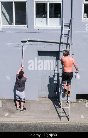 Two men painting the exterior of a building in Newquay in Cornwall in the UK. Stock Photo