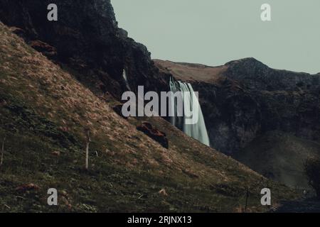 Powerful waterfall cascading down a steep cliff side with lush green ...