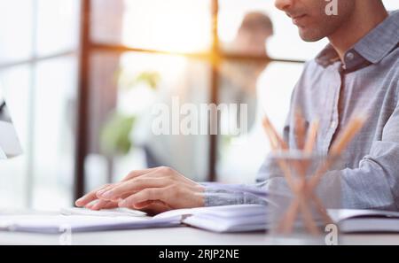 Side view of confident bearded concentrated businessman works on laptop while sitting at the table Stock Photo