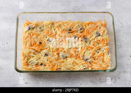 Glass baking dish with raw potato pie, gratin or casserole on gray textured background, top view Stock Photo
