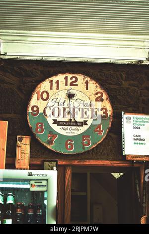An antique looking analog clock hangs on the wall near the entrance of a retail store Stock Photo