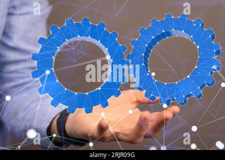 A close-up of a man holding his palm under two blue gear holograms Stock Photo