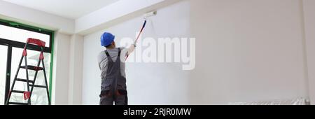 Professional painter paints office wall with roller brush. Stock Photo