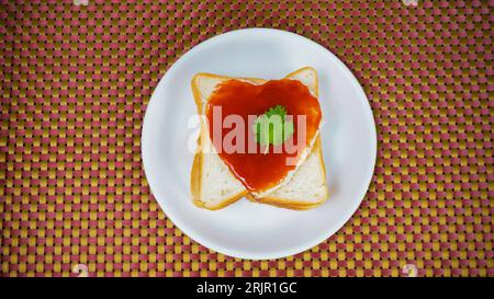 Heart Shape Cutted Bread and Filled with Tomato Sauce with Coriander Leaves in White Dish, on Yellow Woolen Table Mate, Top View Stock Photo