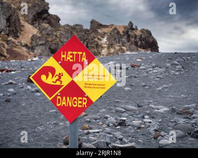 Photo of a warning sign on a rocky beach in Iceland Stock Photo