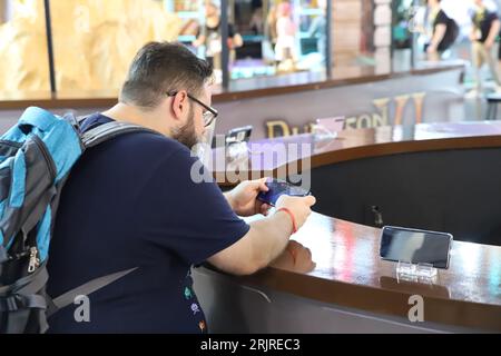 Cologne, Germany. 23rd Aug, 2023. A Gamescom visitor sits at a counter playing a strategy game on a cell phone. Credit: Sascha Thelen/dpa/Alamy Live News Stock Photo