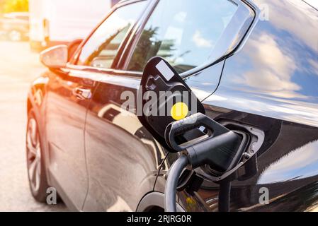 Close up of a cable plugged into an electric car being recharged on a sunny summer day Stock Photo