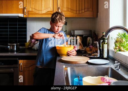 A 10-year-old boy prepares a pie crust, by himself, in the kitchen independently. Stock Photo