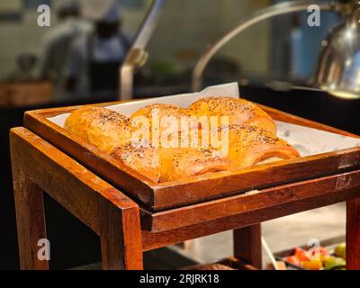 A wooden tray filled with an assortment of freshly-baked croissant buns. Stock Photo