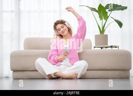 Nice Song. Smiling Young Woman Dancing While Listening Music At Home Stock Photo