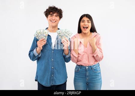 Joyful Young Couple Holding Money Cash Celebrating Financial Luck, Studio Stock Photo