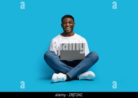 Cheerful millennial black man independent contractor working on laptop Stock Photo
