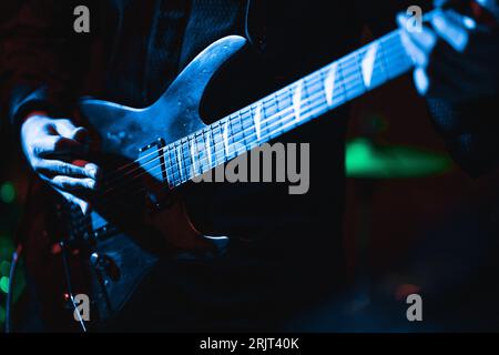 A man playing an electric guitar in a low-lit atmosphere with bright neon colors Stock Photo